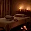 Loş ışıklı spa odasında masaj masası, mum ışığı ve aromaterapi aksesuarları